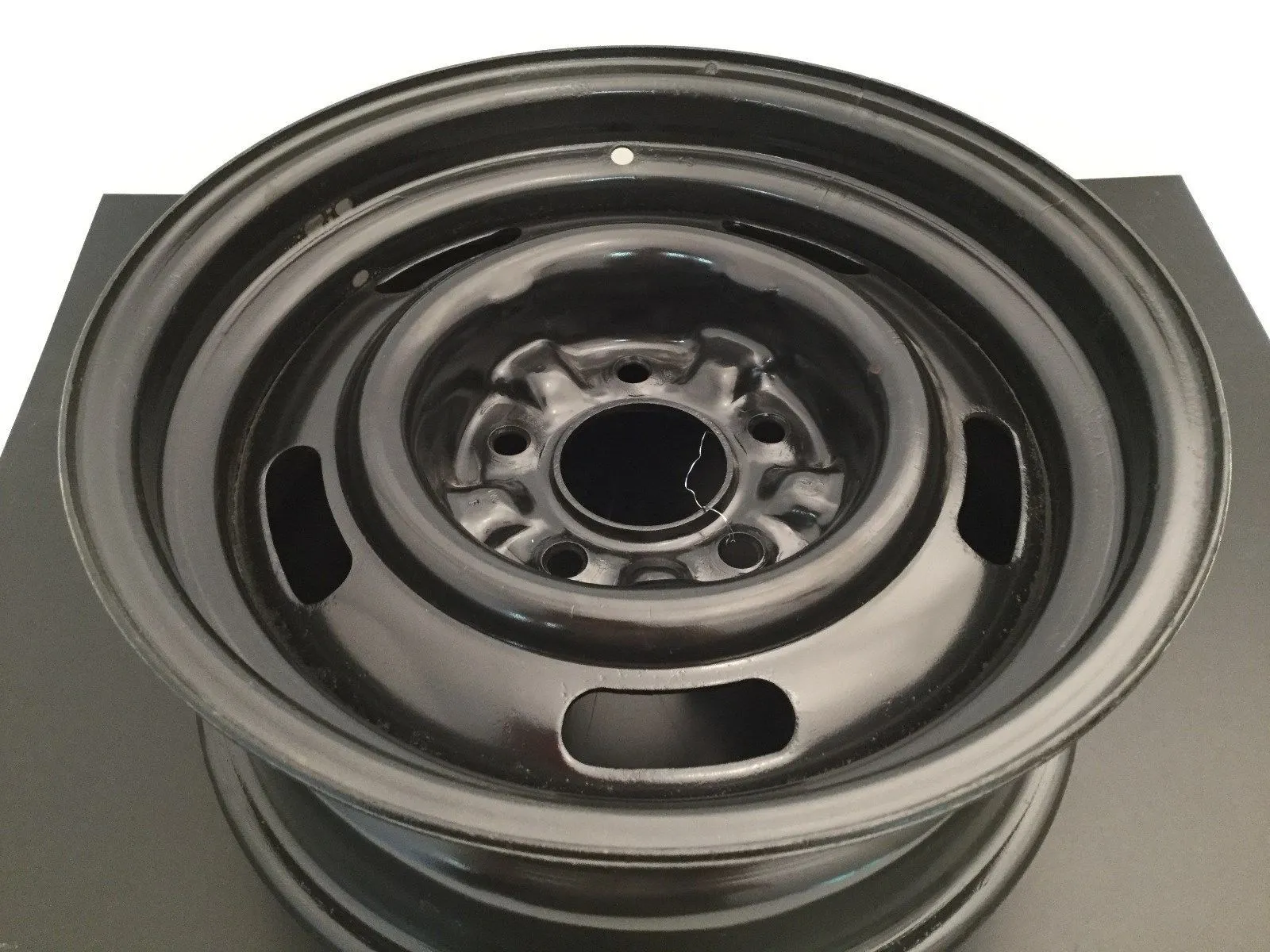 Black car steel wheel rim on gray background.