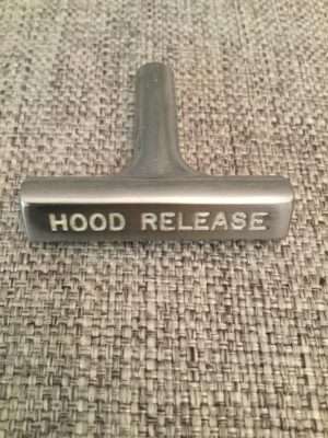 Car hood release lever on textured background.