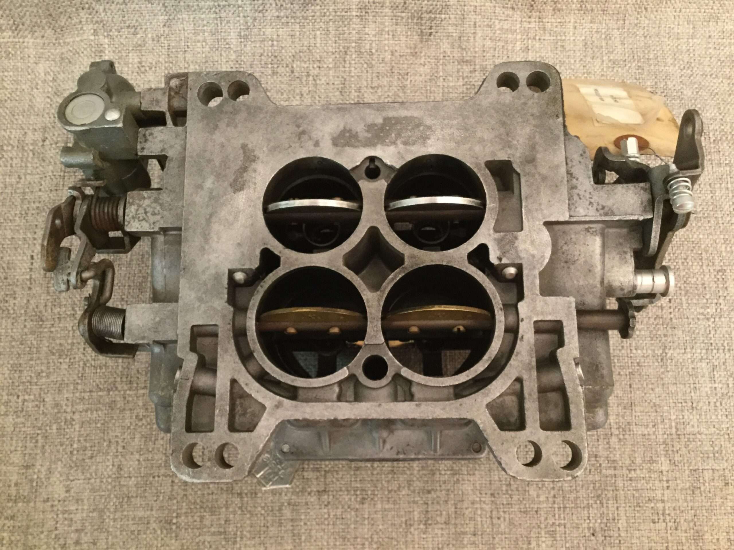 Disassembled automobile carburetor on fabric surface.