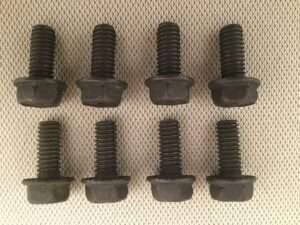 Eight black hex bolts on fabric surface.