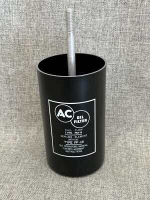 Black AC oil filter with text on fabric background.