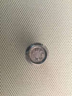 Metal bottle cap on textured surface.