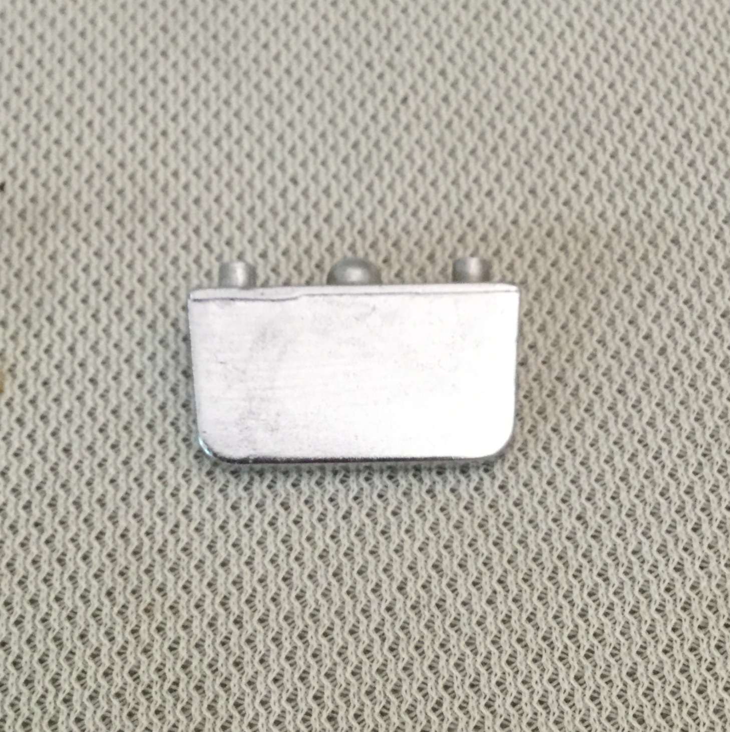 Silver metal clasp on textured fabric.