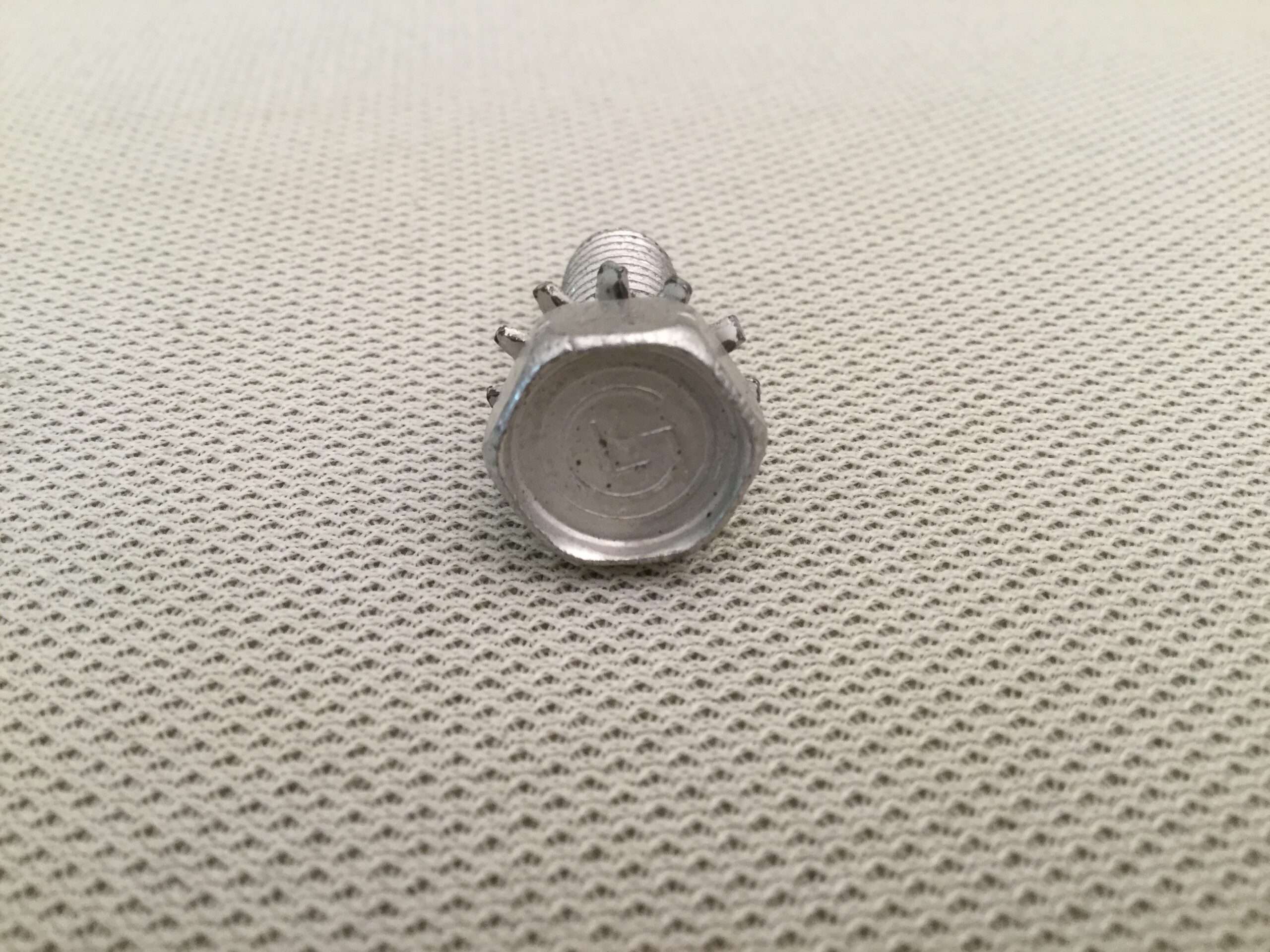 Metal screw on textured surface.