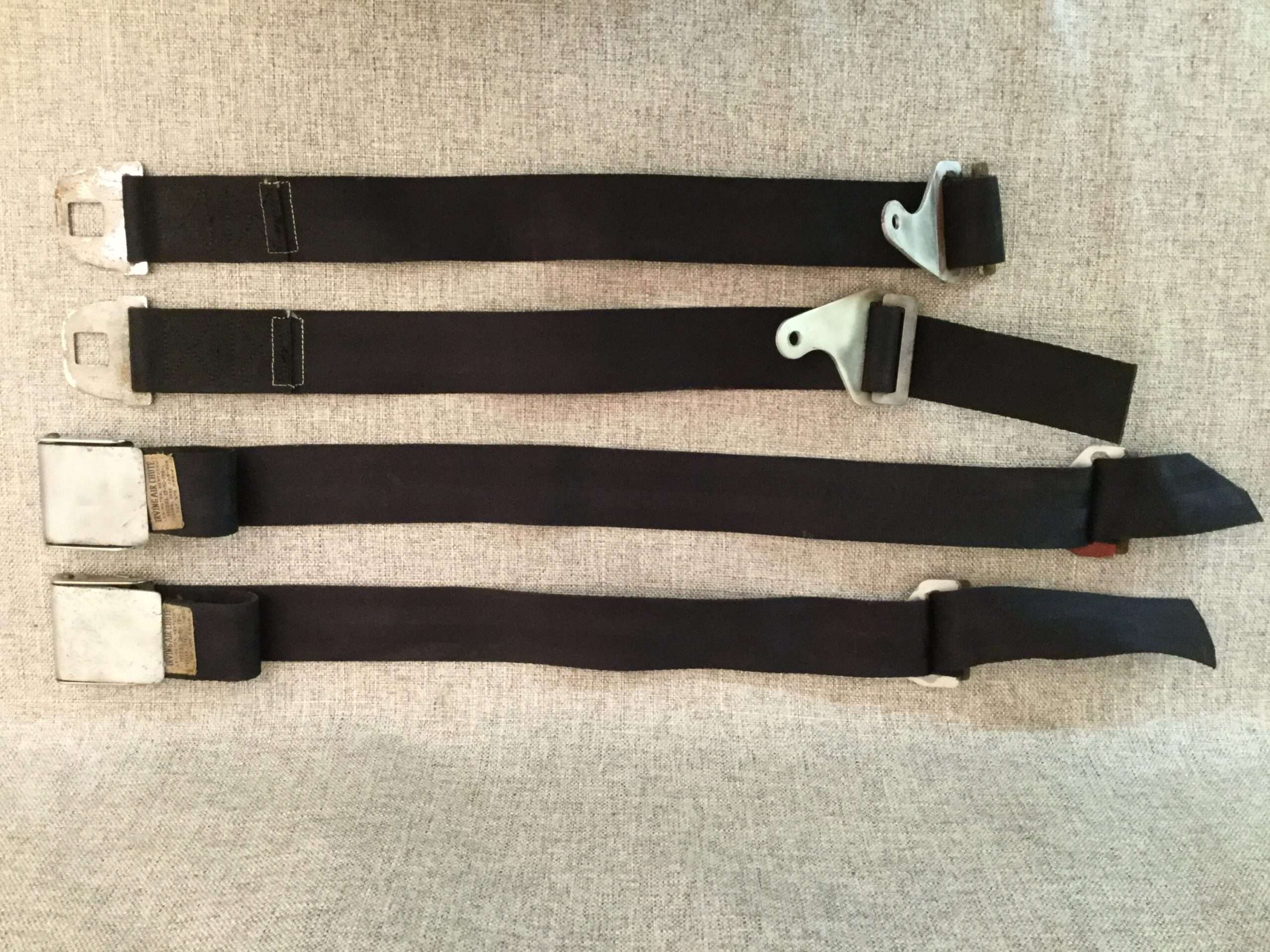 Three various airplane seat belts on fabric.