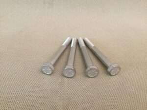 Five metal bolts on beige background.