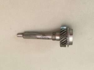 Metal gear and shaft assembly on fabric background.