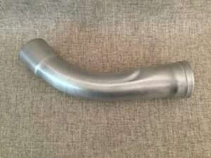 Metal pipe elbow on a fabric background.
