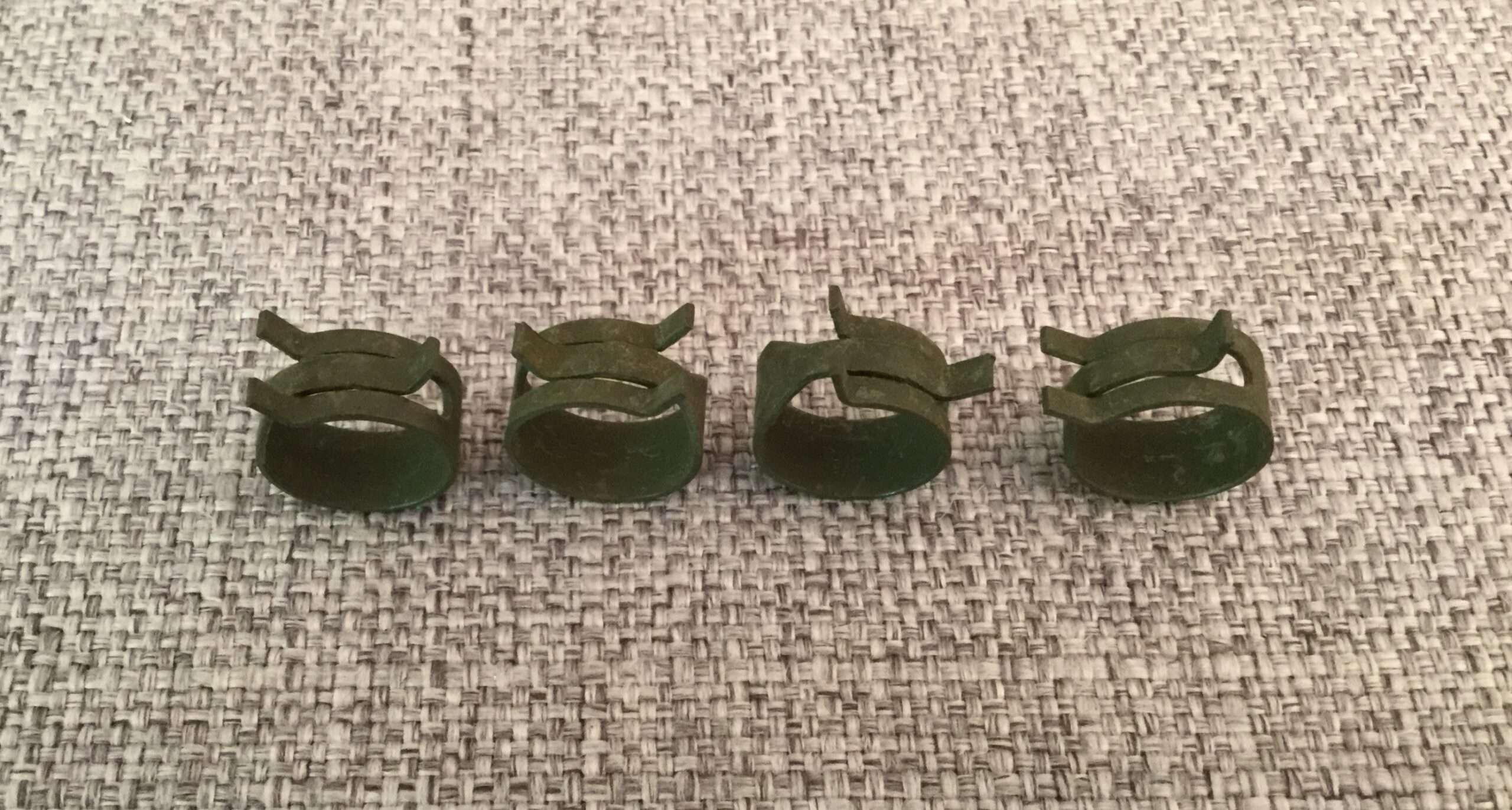 Four green dollar sign paper clips on fabric.