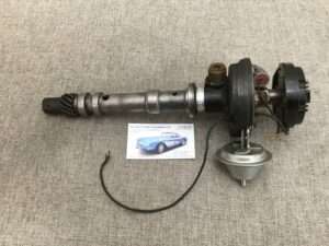 Automotive distributor assembly on carpet with business card.