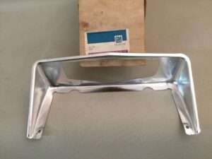 GM car metal grille part on table.
