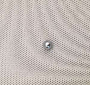 Silver pushpin on textured gray surface.