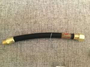 Flexible gas line hose on textured background.